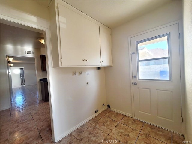 washroom with hookup for a gas dryer, light tile patterned flooring, electric dryer hookup, and cabinets