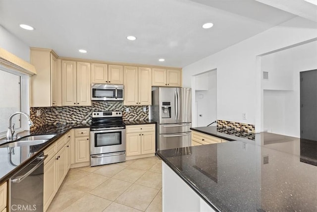 kitchen with backsplash, sink, appliances with stainless steel finishes, light tile patterned floors, and dark stone counters