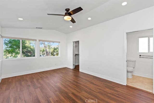 unfurnished bedroom with a spacious closet, hardwood / wood-style flooring, ceiling fan, ensuite bath, and lofted ceiling