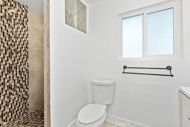 bathroom with toilet, vanity, and a tile shower