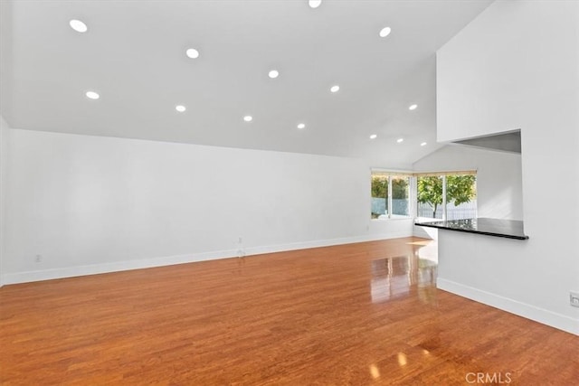 unfurnished living room with high vaulted ceiling and light hardwood / wood-style flooring