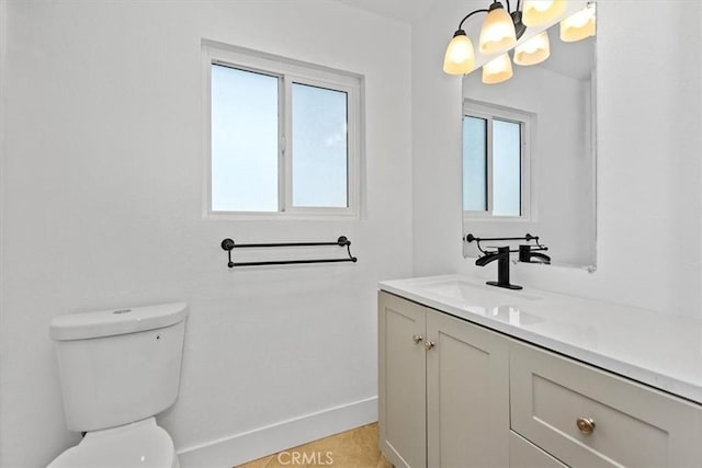 bathroom featuring toilet, vanity, and a notable chandelier