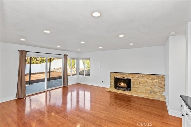 unfurnished living room with light hardwood / wood-style floors and a stone fireplace