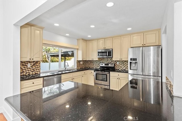 kitchen with decorative backsplash, sink, appliances with stainless steel finishes, and dark stone counters