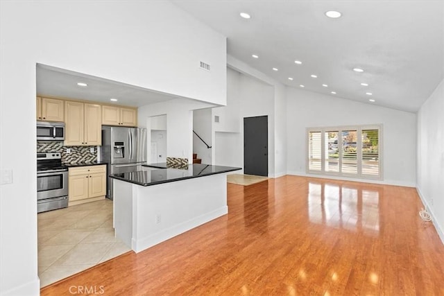 kitchen with high vaulted ceiling, light tile patterned floors, stainless steel appliances, and tasteful backsplash