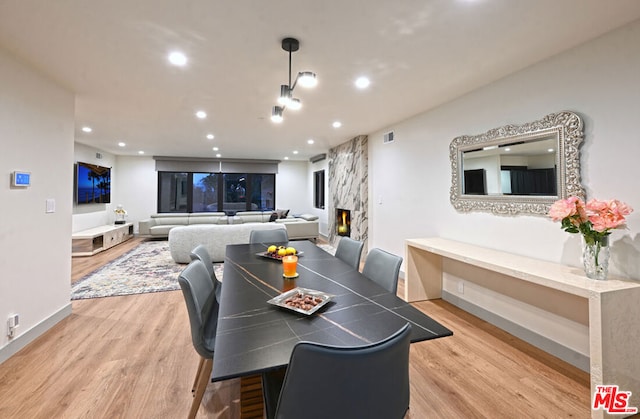 dining area with light wood-type flooring and a premium fireplace