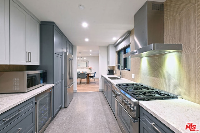 kitchen featuring high end appliances, wall chimney exhaust hood, wine cooler, and gray cabinetry