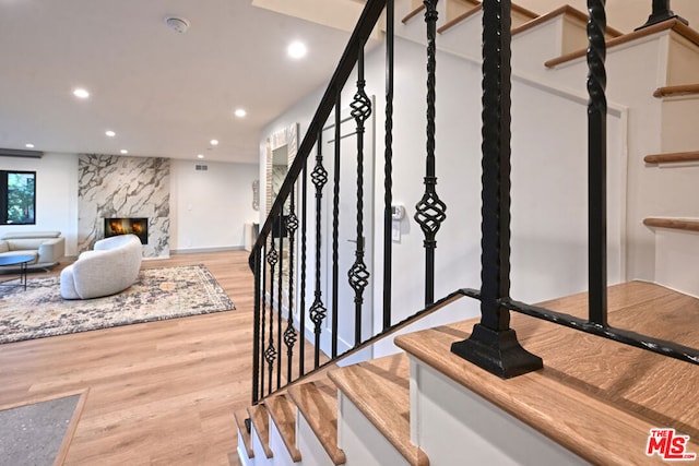 stairs with a premium fireplace and hardwood / wood-style floors