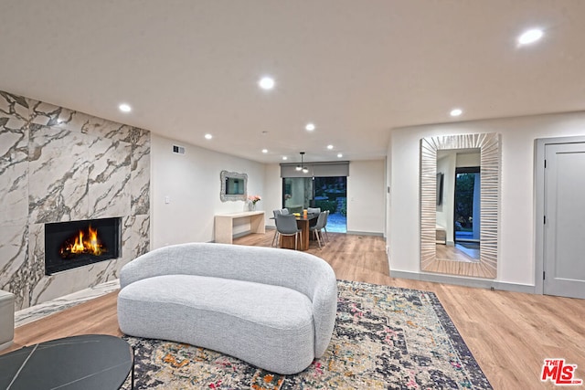 living room with a high end fireplace and light wood-type flooring