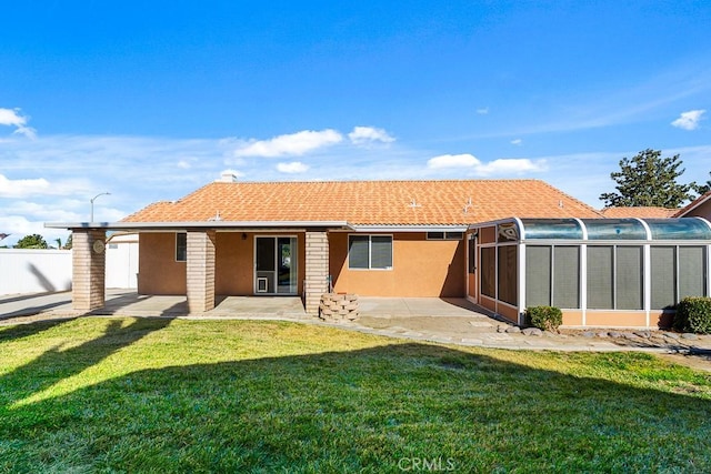 back of house with a sunroom, a lawn, and a patio