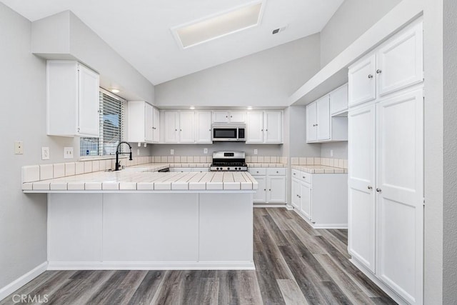 kitchen with white cabinetry, kitchen peninsula, stainless steel appliances, dark hardwood / wood-style floors, and sink