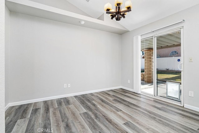 empty room with lofted ceiling, a chandelier, and hardwood / wood-style flooring