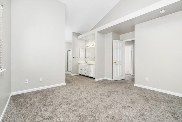 unfurnished bedroom with light colored carpet, lofted ceiling, and ensuite bath