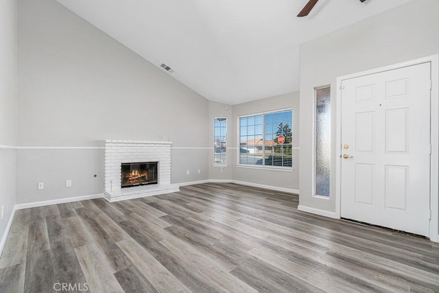 unfurnished living room featuring light wood-type flooring, a brick fireplace, lofted ceiling, and ceiling fan