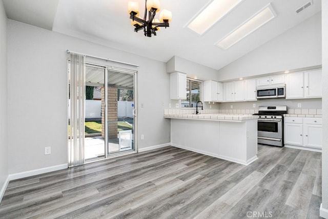 kitchen featuring kitchen peninsula, white cabinetry, stainless steel appliances, and a healthy amount of sunlight