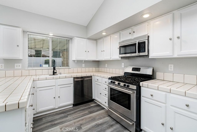 kitchen with appliances with stainless steel finishes, tile countertops, and white cabinets