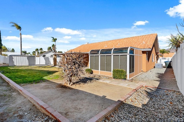 rear view of house featuring a sunroom, a lawn, and a patio