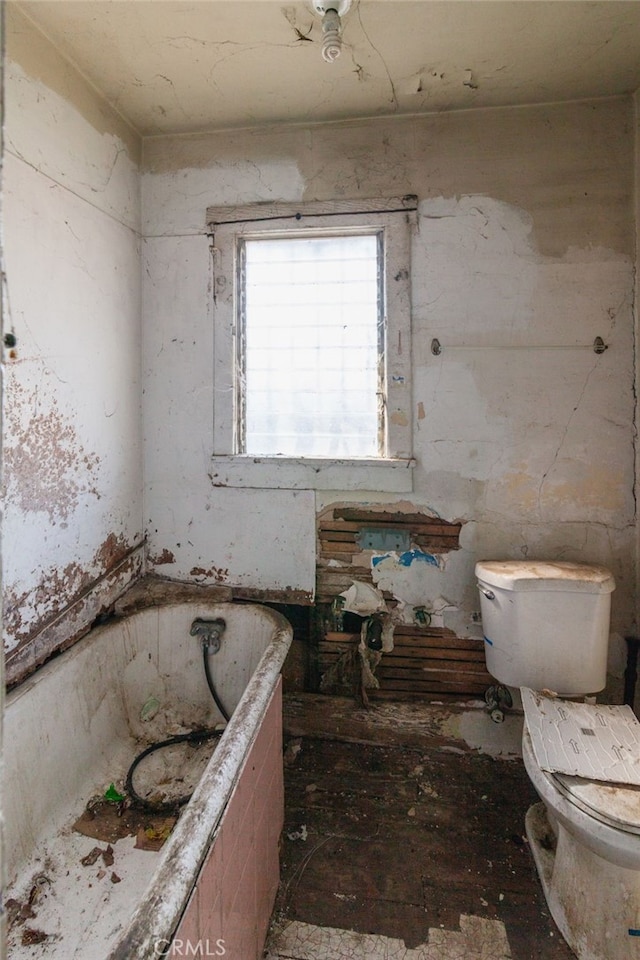 bathroom featuring toilet and a tub to relax in