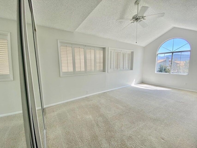 unfurnished room with vaulted ceiling, ceiling fan, and light carpet