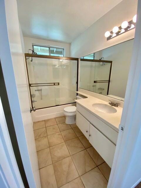 full bathroom featuring tile patterned floors, toilet, shower / bath combination with glass door, and vanity