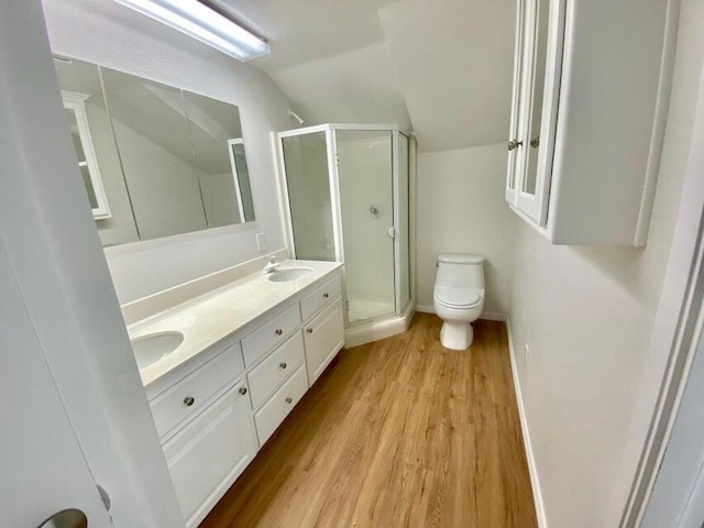 bathroom featuring toilet, hardwood / wood-style floors, lofted ceiling, walk in shower, and vanity