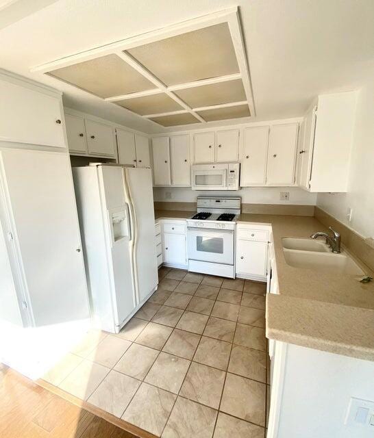 kitchen featuring white cabinetry, sink, white appliances, and light tile patterned floors