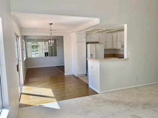 kitchen featuring decorative light fixtures, white cabinets, white appliances, and a textured ceiling