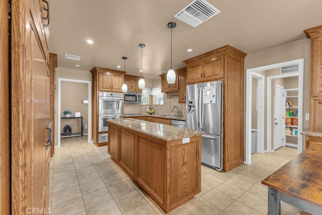 kitchen with decorative light fixtures, light stone counters, a center island, and stainless steel appliances