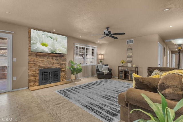 tiled living room featuring a fireplace and ceiling fan