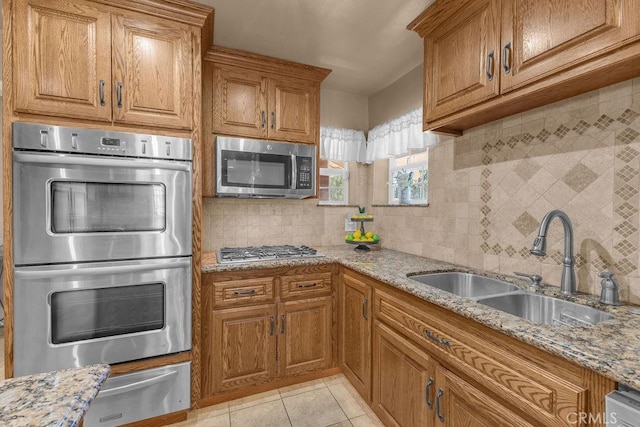 kitchen featuring sink, light stone countertops, appliances with stainless steel finishes, and decorative backsplash