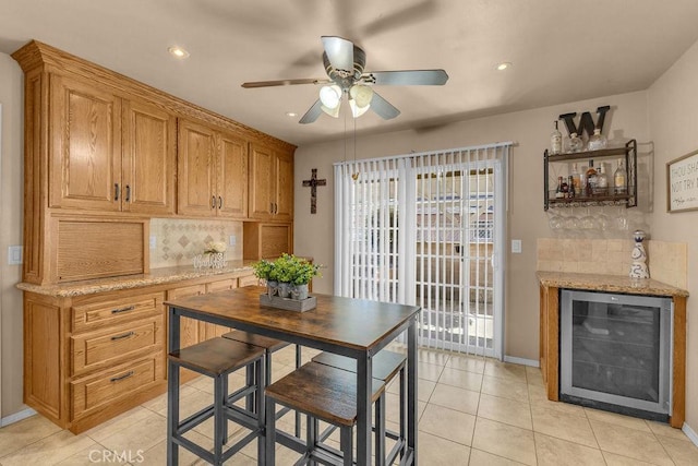 tiled dining room featuring ceiling fan, bar area, and beverage cooler