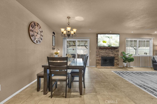 dining area featuring a textured ceiling, a chandelier, light tile patterned floors, and a stone fireplace