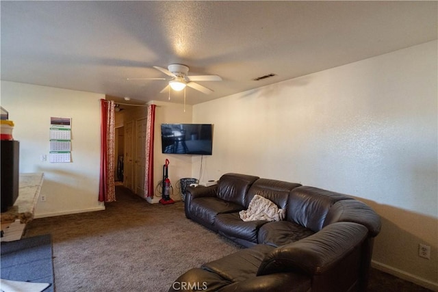 living room with a textured ceiling, dark colored carpet, and ceiling fan