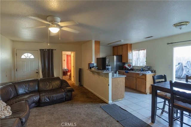 living room with ceiling fan, a textured ceiling, and light carpet