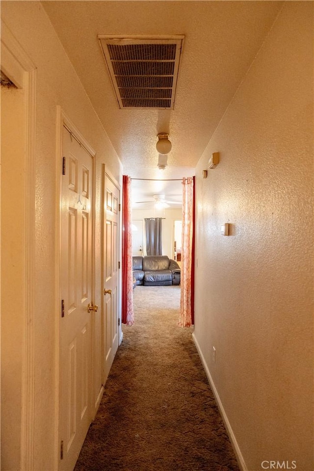 hallway featuring a textured ceiling and carpet flooring