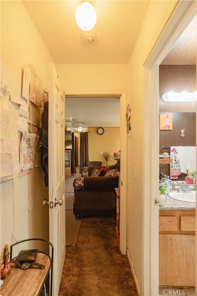 hall with sink and dark carpet