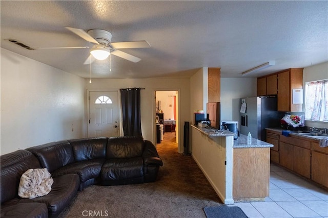 kitchen featuring a textured ceiling, sink, stainless steel fridge, ceiling fan, and light tile patterned floors