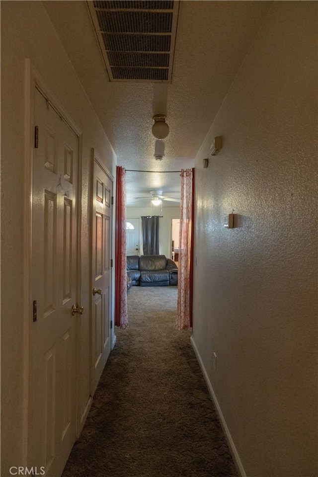 hallway featuring carpet floors and a textured ceiling