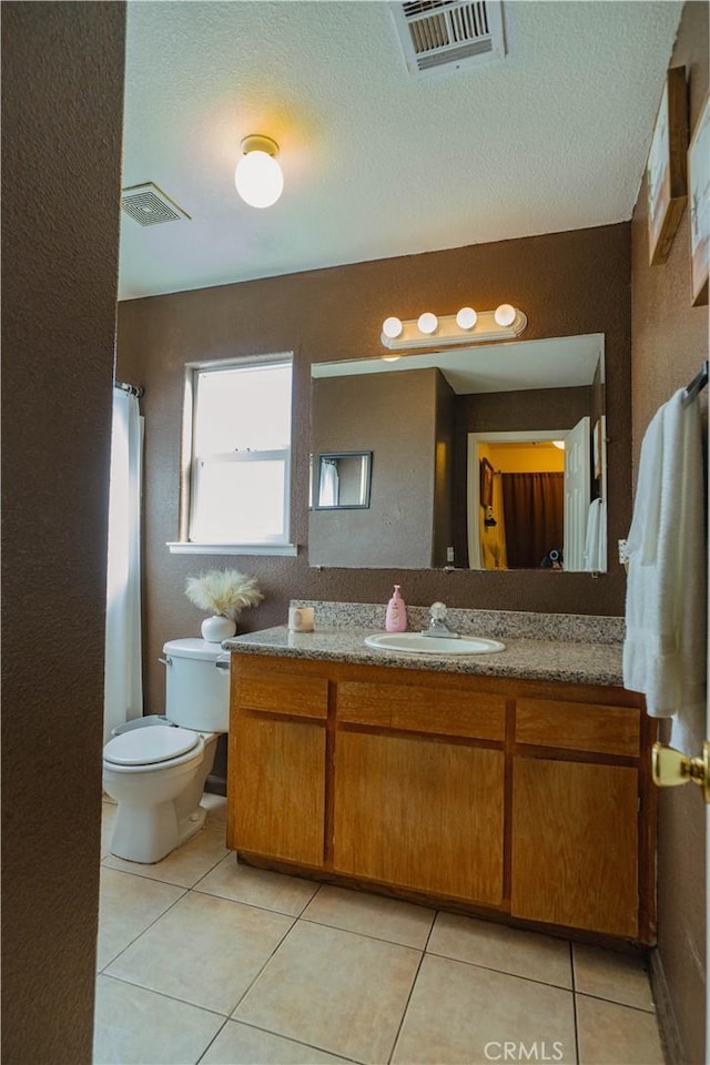 bathroom featuring toilet, vanity, tile patterned floors, and a textured ceiling