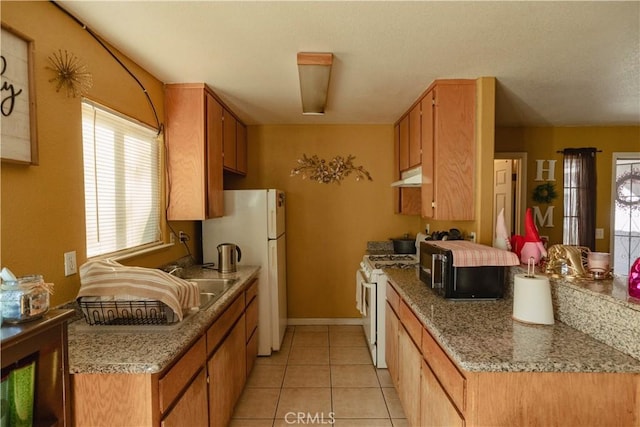 kitchen featuring light stone countertops, white appliances, and light tile patterned floors