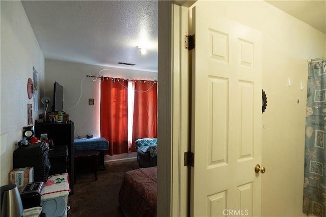 bedroom with a textured ceiling and dark colored carpet