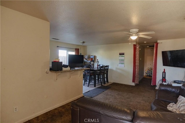 living room with a textured ceiling, ceiling fan, and carpet