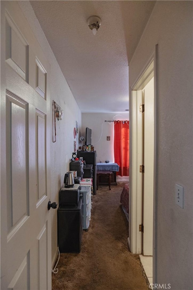 hallway with a textured ceiling and carpet flooring