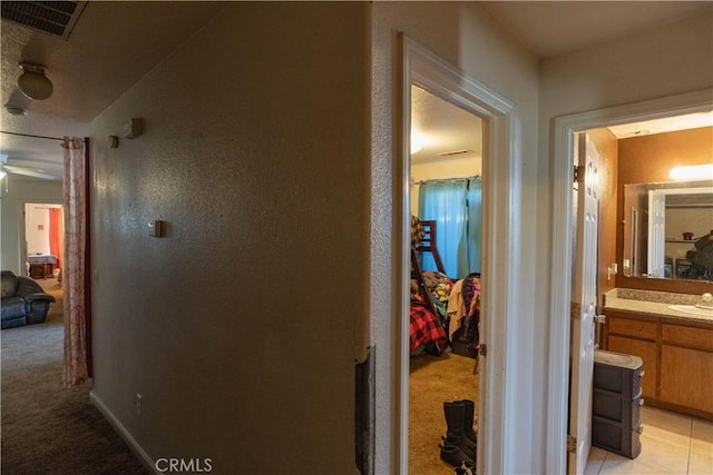 hallway featuring light colored carpet and sink