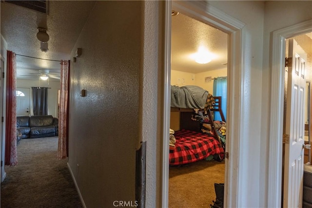 corridor featuring a textured ceiling and carpet flooring