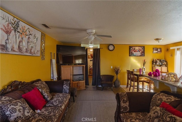 living room with a textured ceiling and ceiling fan