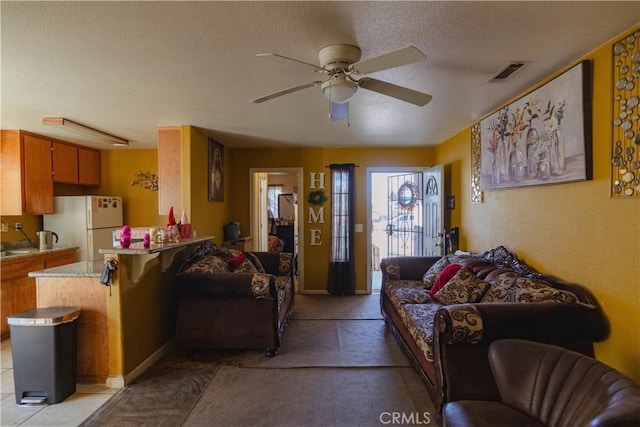 living room with ceiling fan and a textured ceiling