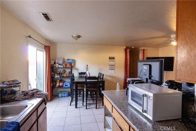 kitchen featuring a textured ceiling, ceiling fan, light tile patterned floors, and sink