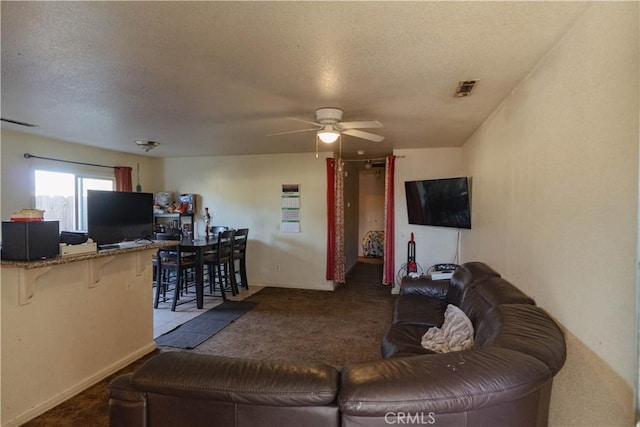 carpeted living room featuring a textured ceiling and ceiling fan