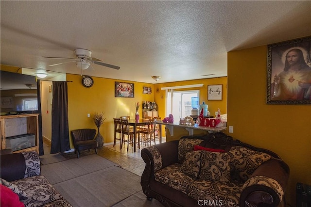 living room featuring ceiling fan, a textured ceiling, and a fireplace